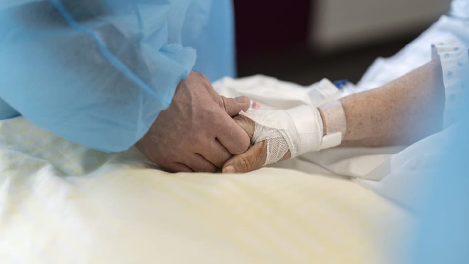 Eine Pflegefachperson drückt die Hand einer Patientin