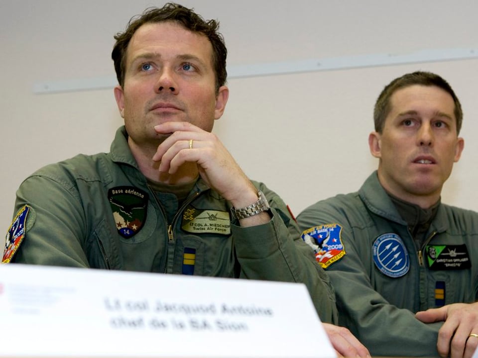 Zwei Männer in Uniform, als Militärpiloten erkennbar. 