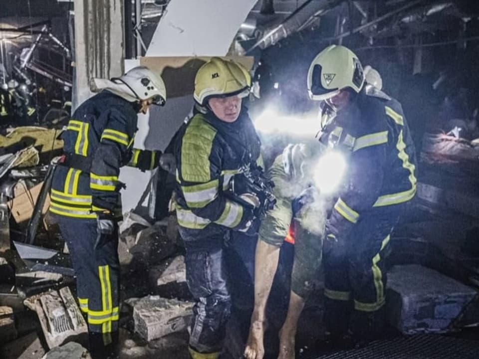 Nach einem Luftangriff tragen Einsatzkräfte einen Verletzten aus einem Einkaufszentrum in Kiew. (21. März 2022)