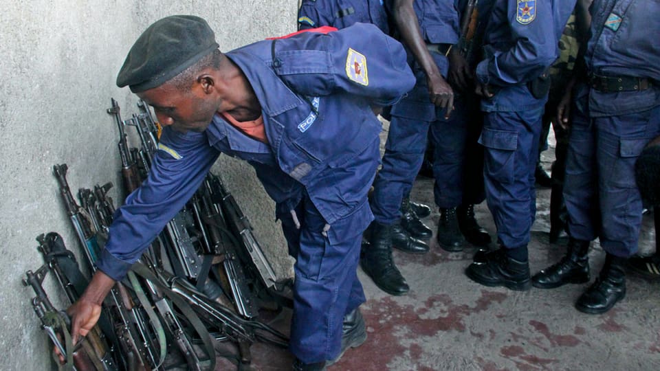 Kongolesische Polizisten stellen ihre Waffen an eine Wand.