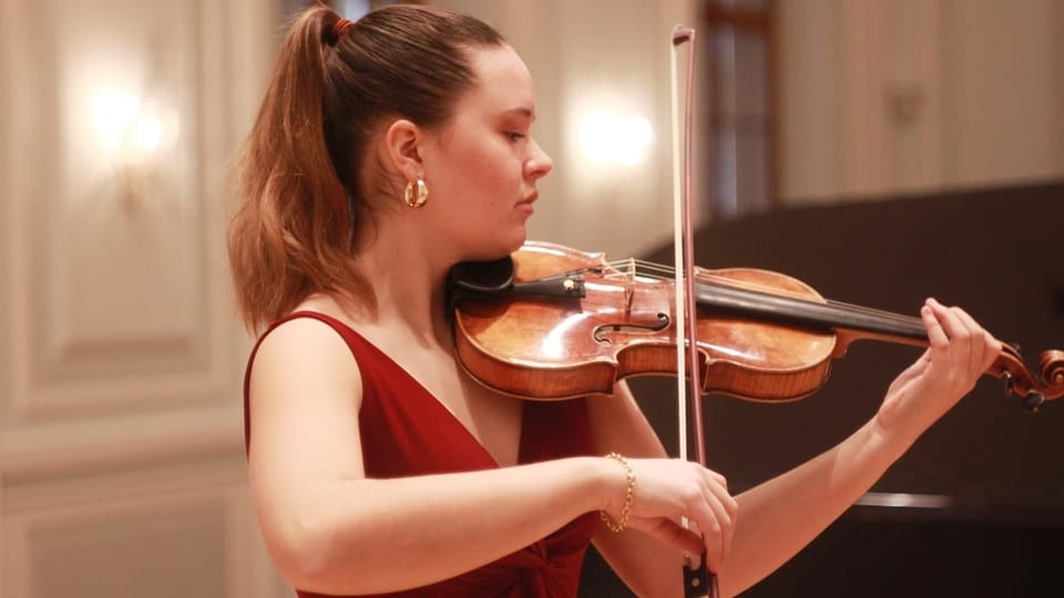 junge Frau in rotem Kleid und Pferdeschwanz spielt Geige.