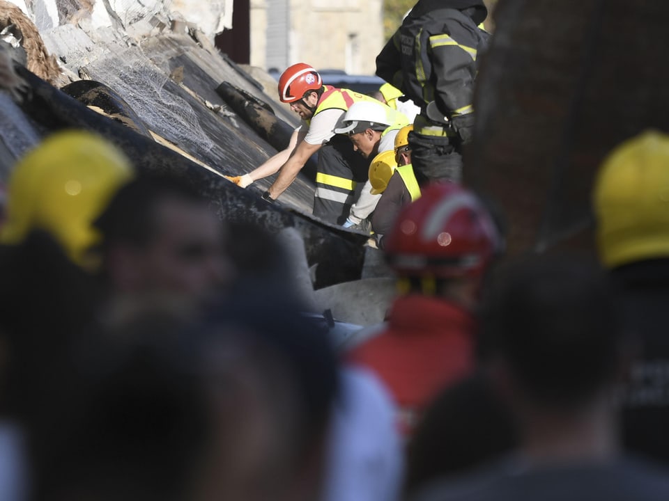 Bombeiros trabalham em uma estrutura de prédio desabada.