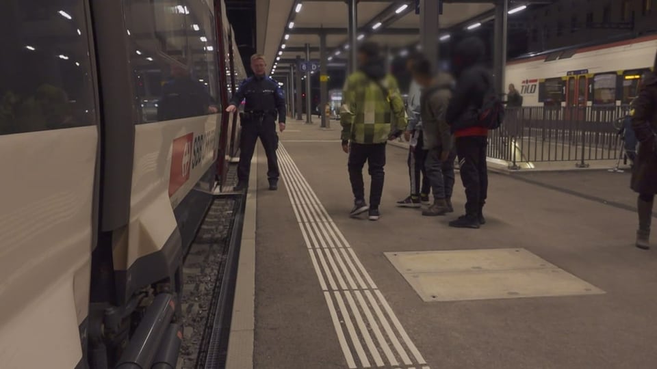 Ein Grenzwächter hält die Türe eines Zugs offen, für Migranten die auf dem Peron stehen. 