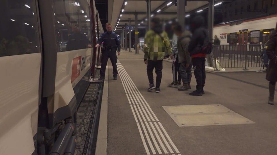 Ein Grenzwächter hält die Türe eines Zugs offen, für Migranten die auf dem Peron stehen.