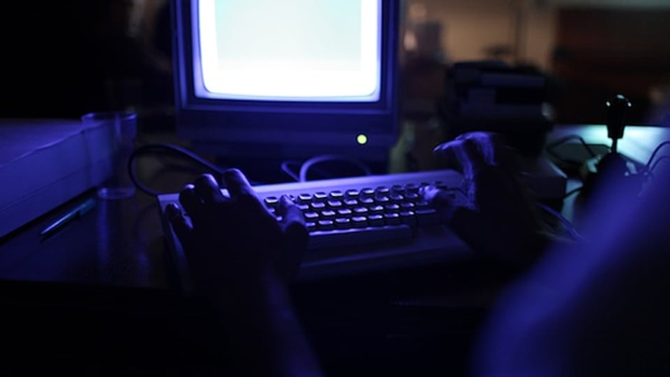 Ein Commodore-64-Veteran bedient das Keyboard im dunklen Vereinslokal.