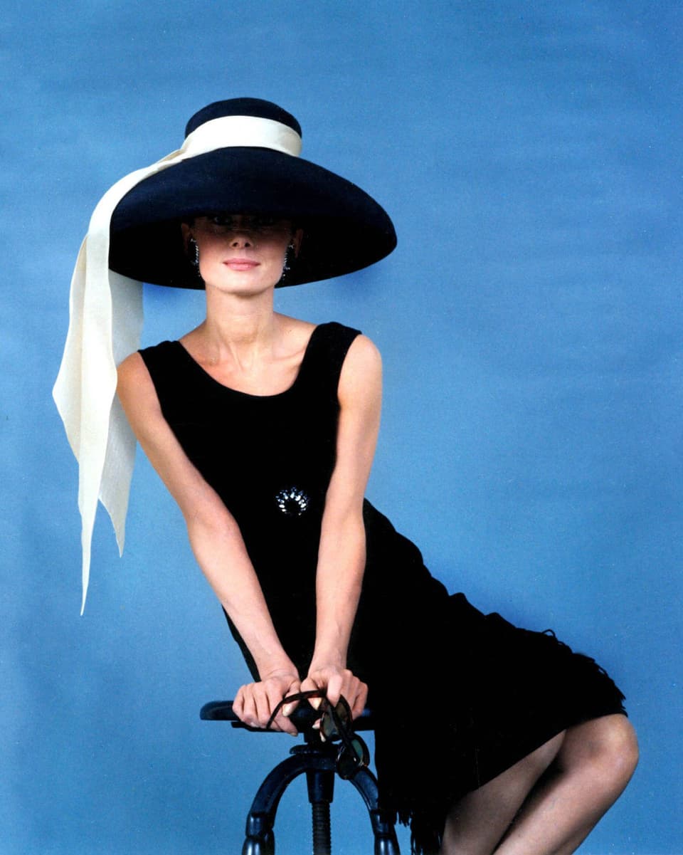 Audrey Hepburn mit kurzem schwarzen Kleid und Hut.