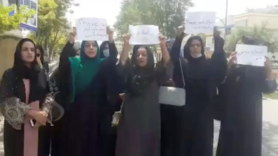 Eine Gruppe von Frauen protestiert mit kleinen Schildern.