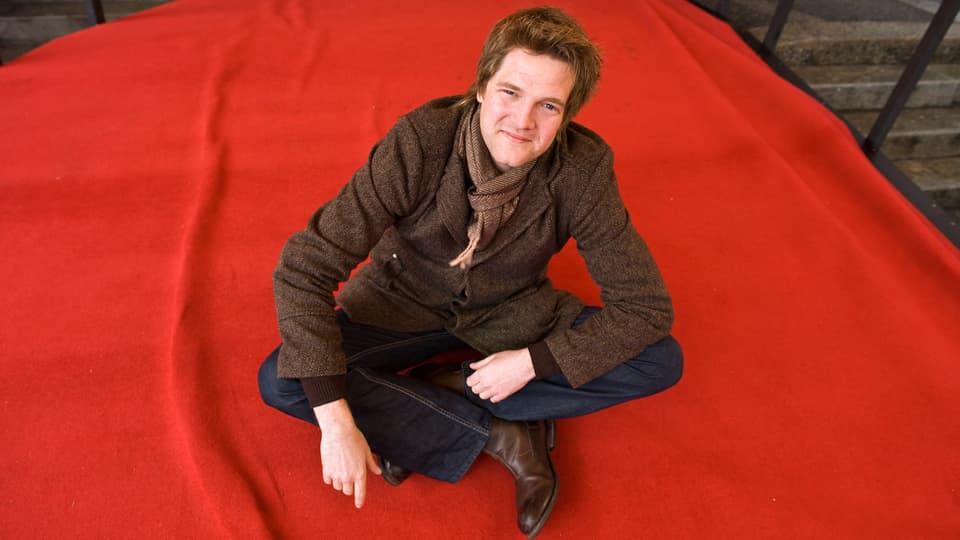 Reto Caffi sitzt auf rotem Teppich.