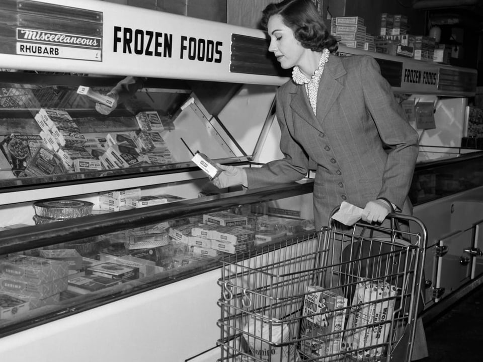 Frau in einem Anzug kauft Tiefkühlkost im Supermarkt.