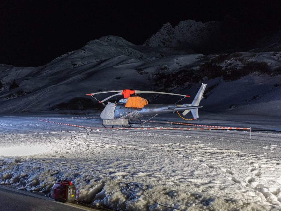 Ein abgedeckter Hubschrauber steht im Schnee.