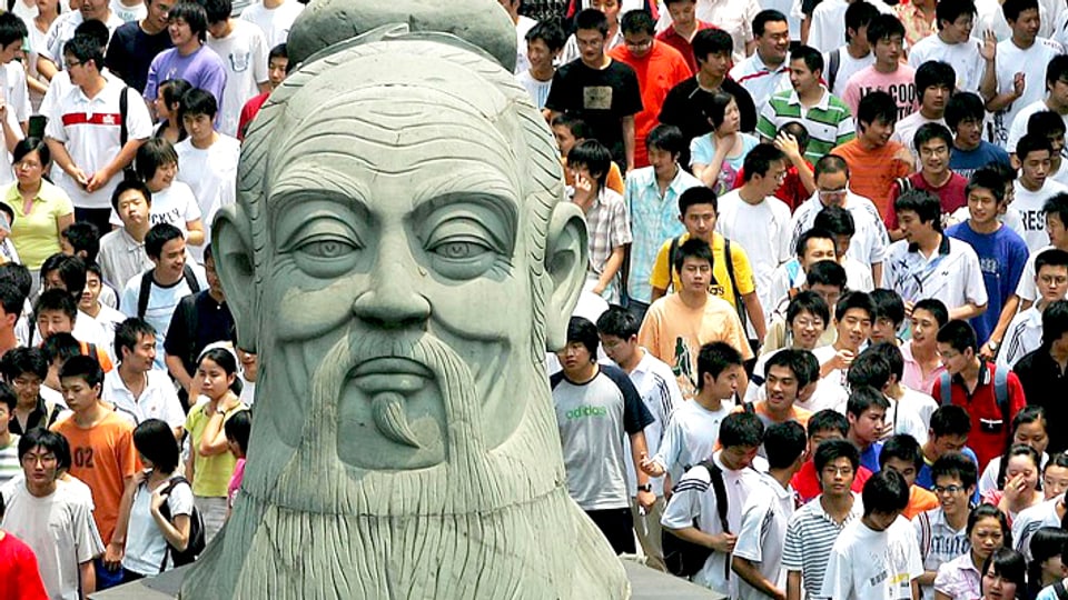 Junge Chinesen gehen an einer riesigen Büste von Konfuzius vorbei.
