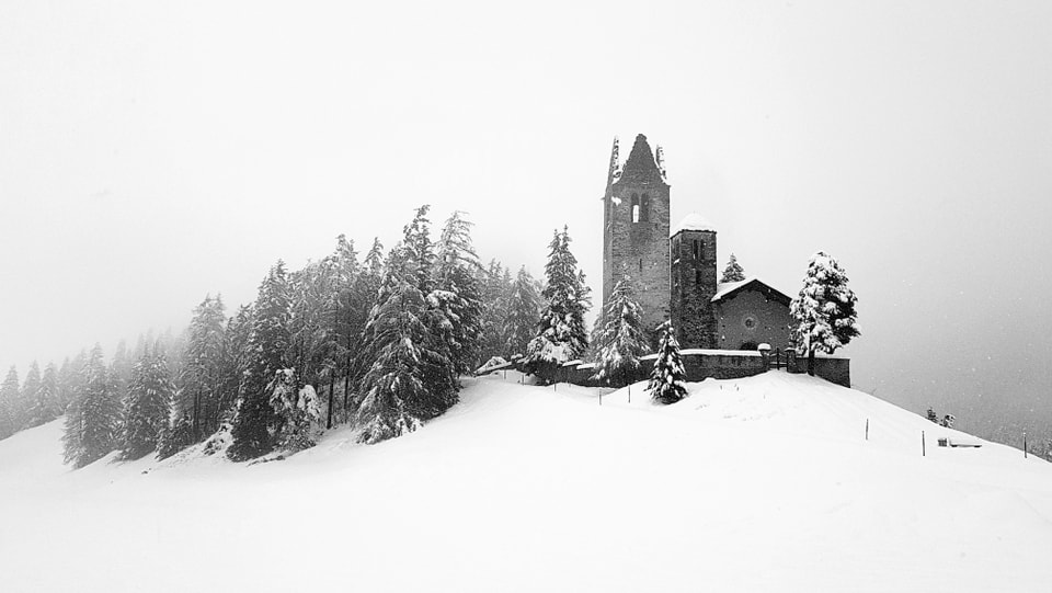 Blick auf die verschneite Landschaft bei Celerina mt einer Kirchenruine.