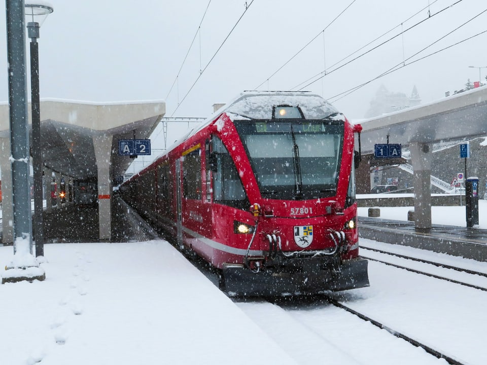 Die Bahn steht am Bahnhof in St. Moritz, es schneit.