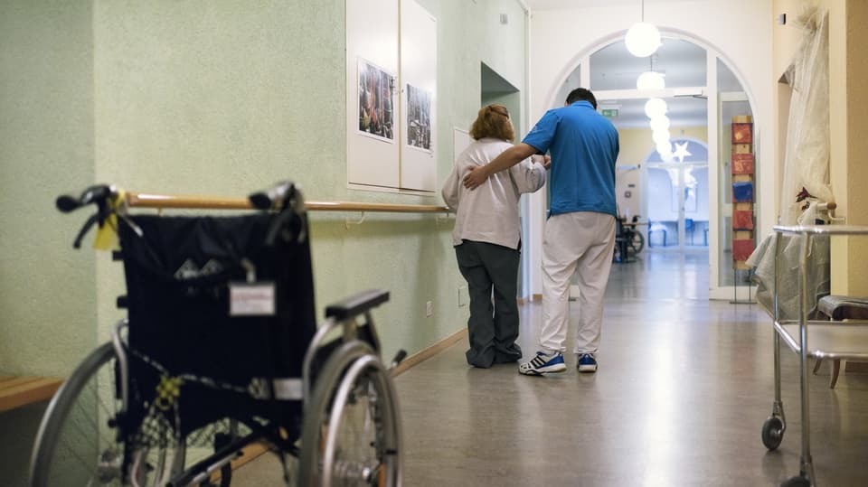 Eine Pflegekraft hilft einer älteren Person aus dem Rollstuhl.