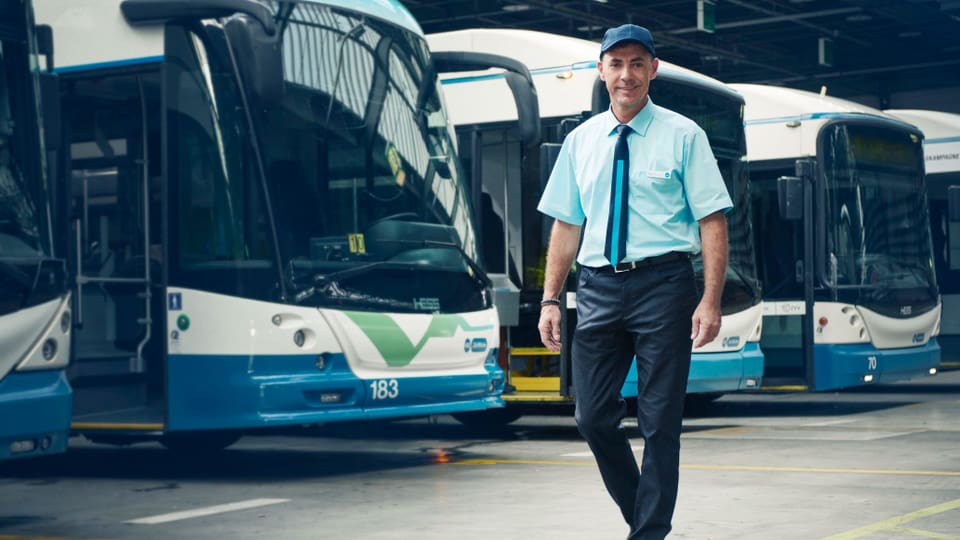 Ein VBZ-Angestellter in dunkelblauer Hose, hellblauem Hemd, blau - hellblauer Krawatte und blauer Mütze.