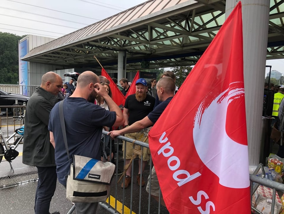 Männer an einer Absperrung, rote Flagge