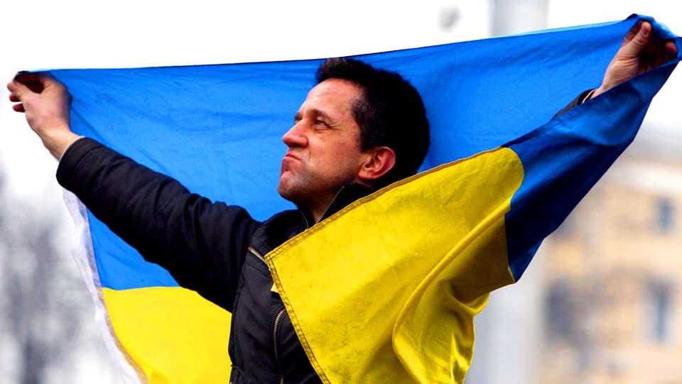 Ein Mann hält die ukrainische Flagge.