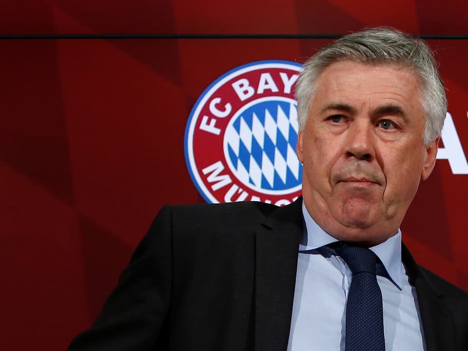 Carlo Ancelotti posiert vor dem Bayern-Logo.