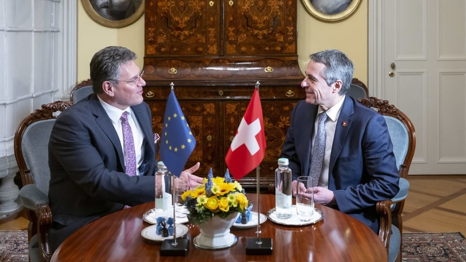 Sefcovic und Cassis am Tisch. Sie scheinen sich sympathisch zu sein. Es steht ein Blumenstrauss dort, EU- und CH-Flagge.