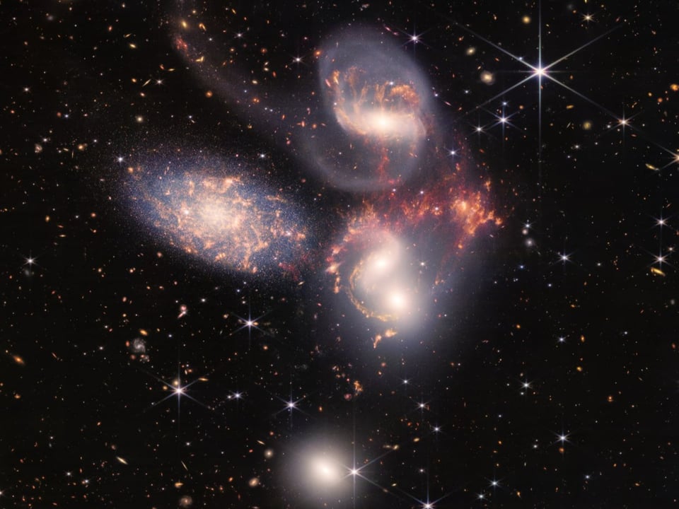 Fünf unterschiedlich gefärbte Galaxien im All.