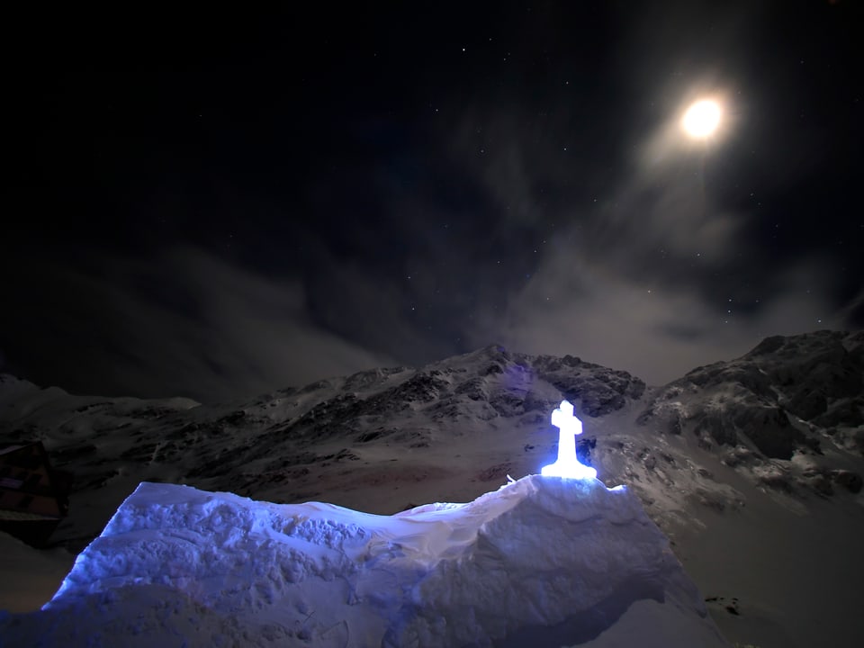 Der Mond scheint auf eine Kirche aus Eis in den schneebedeckten Bergen des Fagaras-Gebirges in Rumänien.