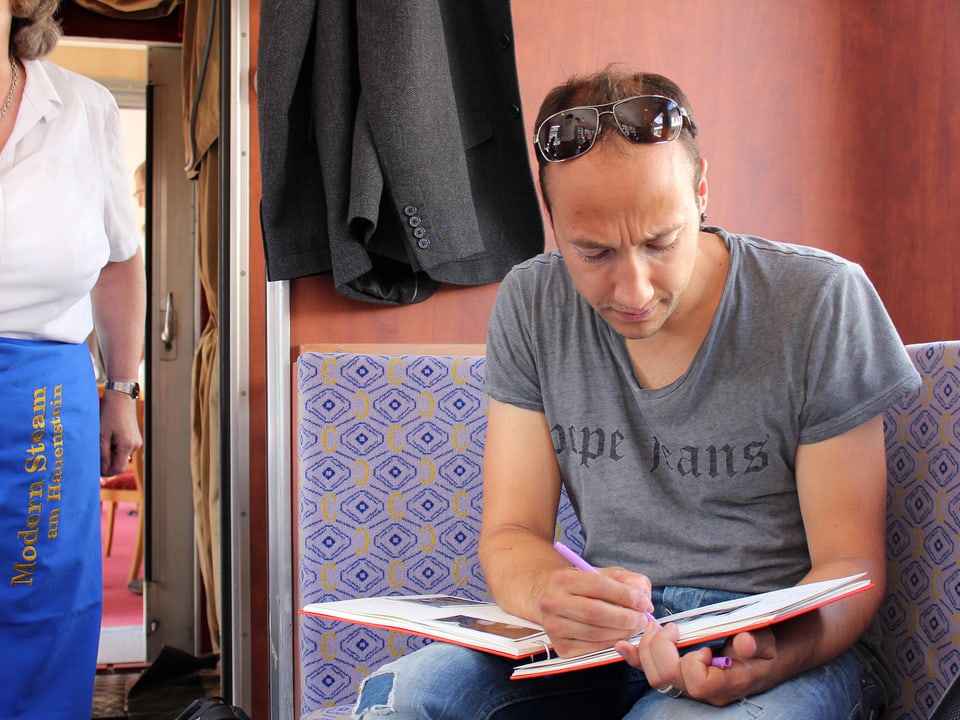 Ritschi schreibt seinen Tagebucheintrag im Zug sitzend.