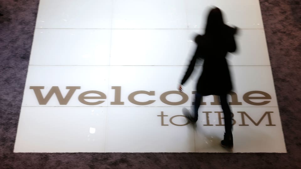 Die Silhouette einer Frau, die über ein IBM-Logo am Boden schreitet.