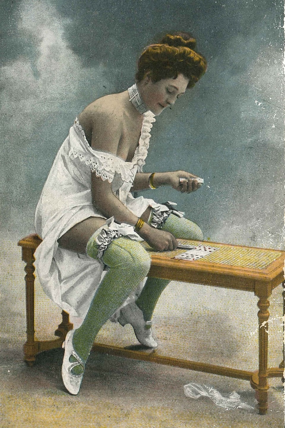 Eine Dame sitzt auf einer Bank und spielt Karten.