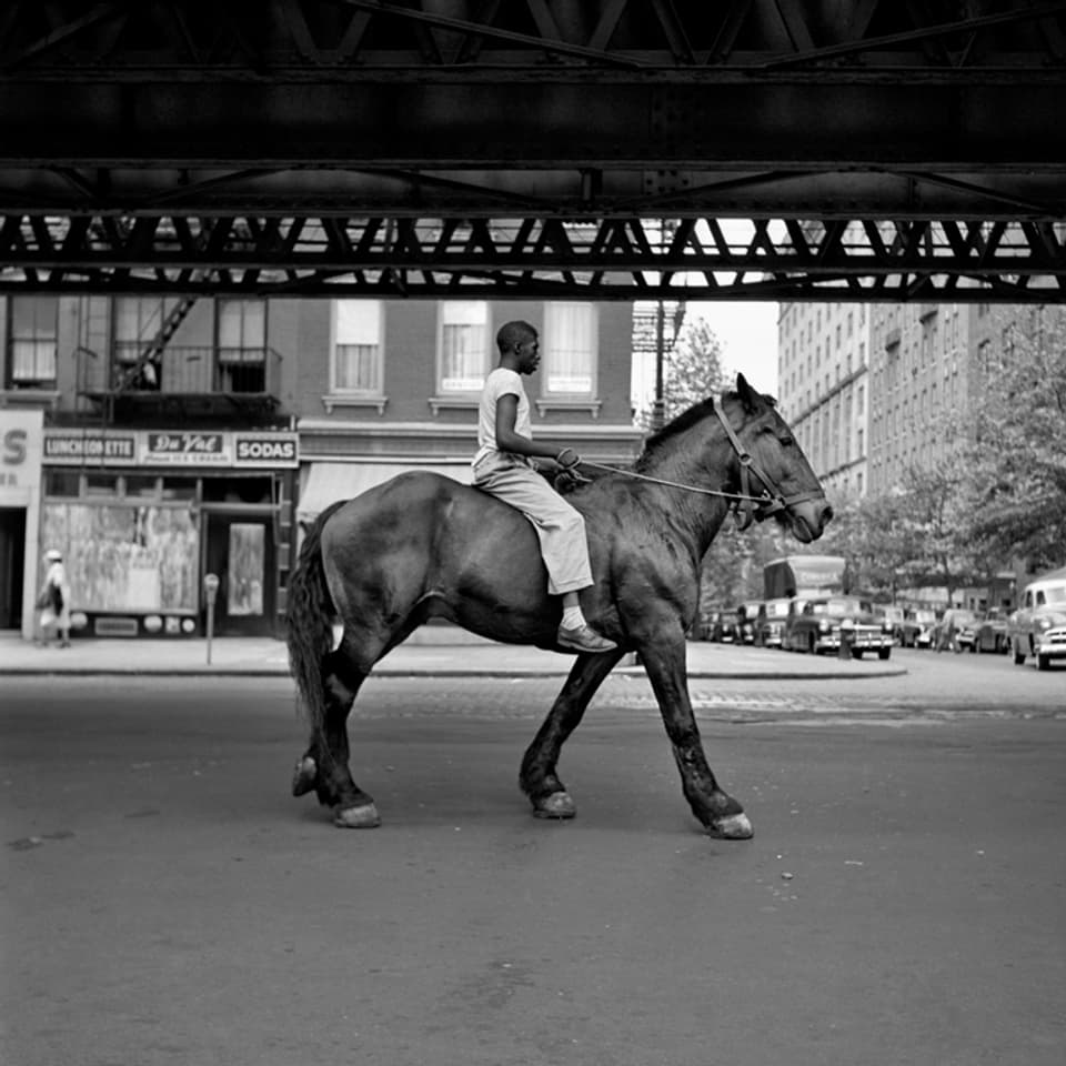 schwarz weiss fotografie. ein schwarzer mann reitet auf einem pferd durch die strassen von New York