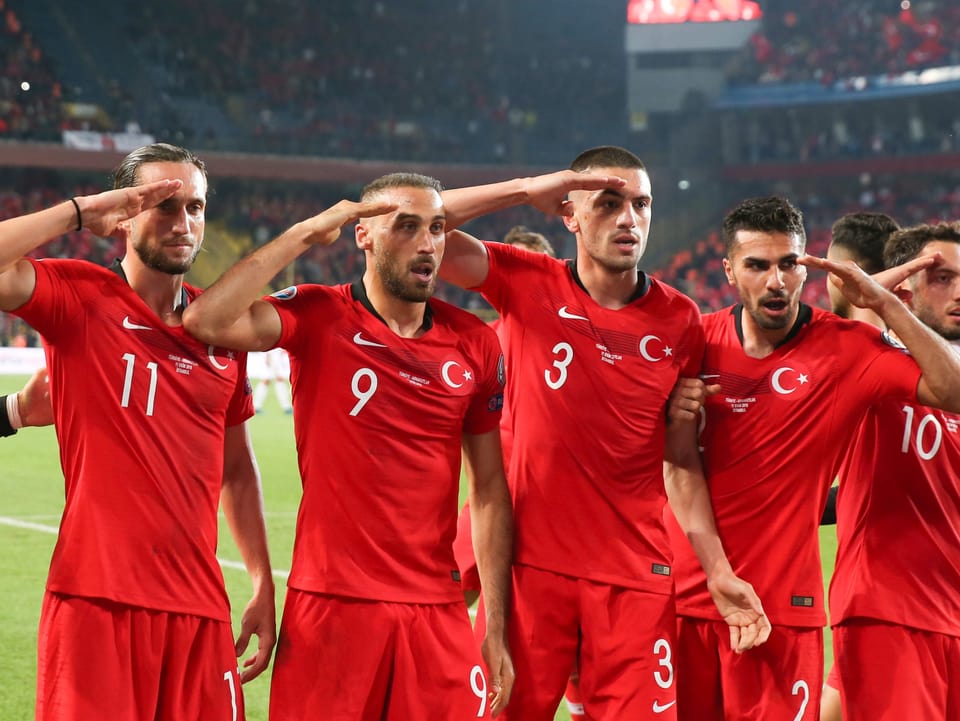 Die türkischen Fussballer greifen mit der rechten Hand an die Stirn.