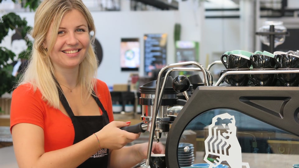 Eine Frau macht Kaffee mit einer professionellen Maschine.