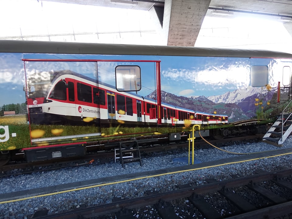 Ein Bahnwagen mit einem Aufdruck, der einen Zug vor Alpenpanorama zeigt.