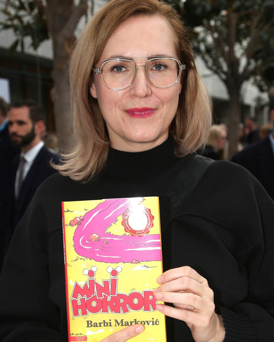 Die Autorin mit Brille und schwarzem Rollkragenpullover hält ihr Buch «Minihorror» in die Kamera.