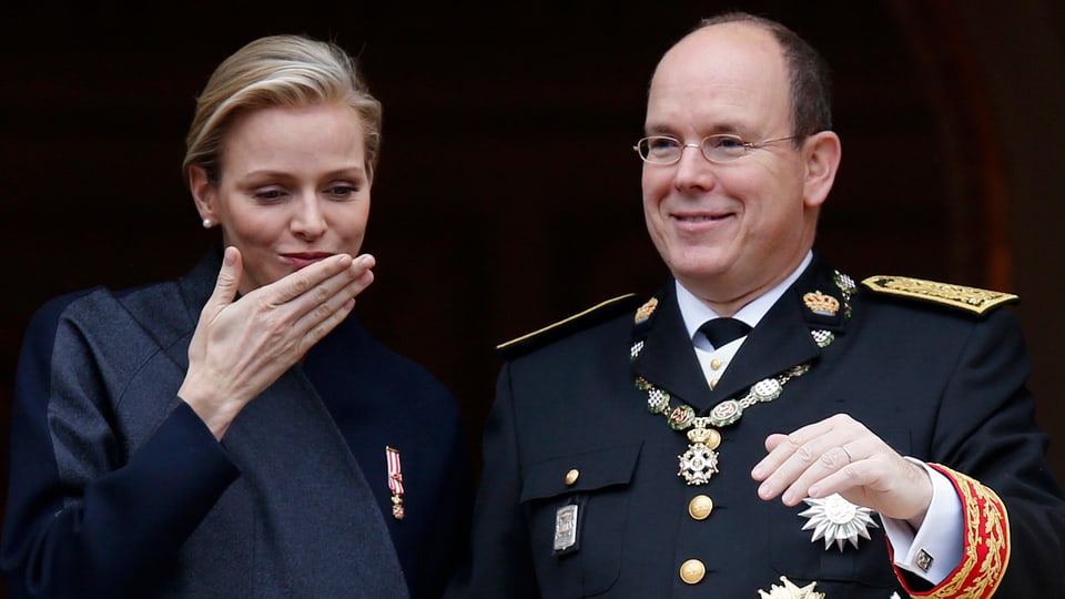 Fürstin Charlène und Fürst Albert lächelnd nebeneinanderstehend.