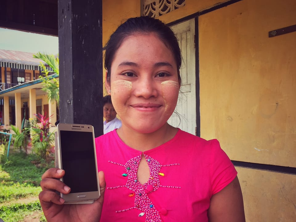 Junge Frau in Burma zeigt ihr Smartphone.