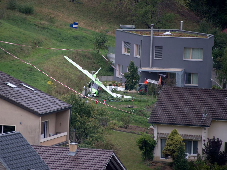 Ein abgestürztes Kleinflugzeug liegt im Garten vor einem Haus