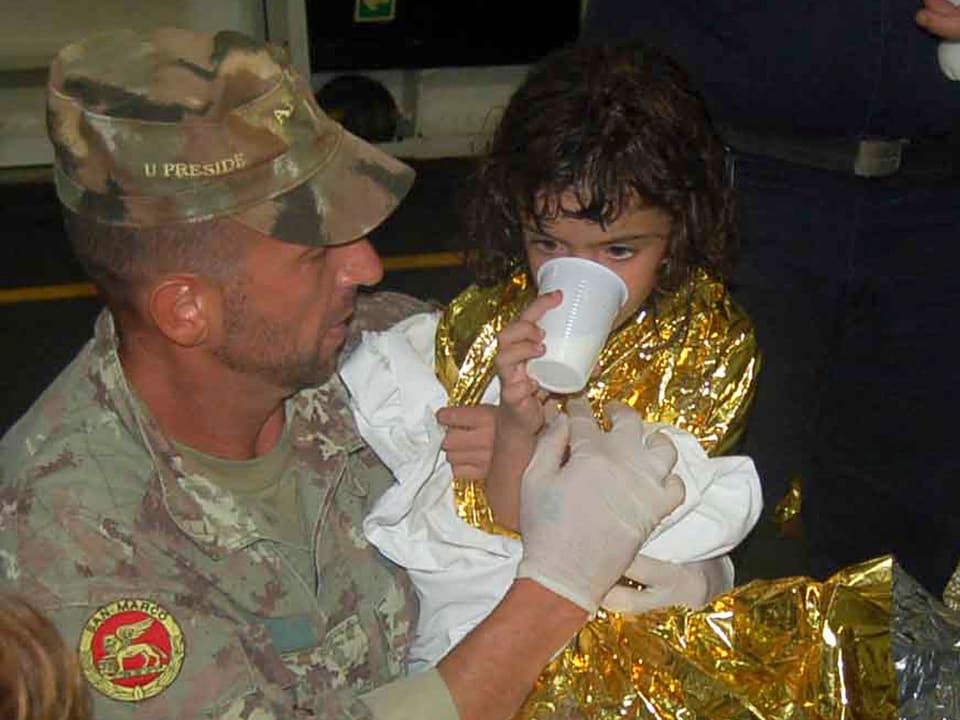 Ein Soldat gibt einen Mädchen zu trinken
