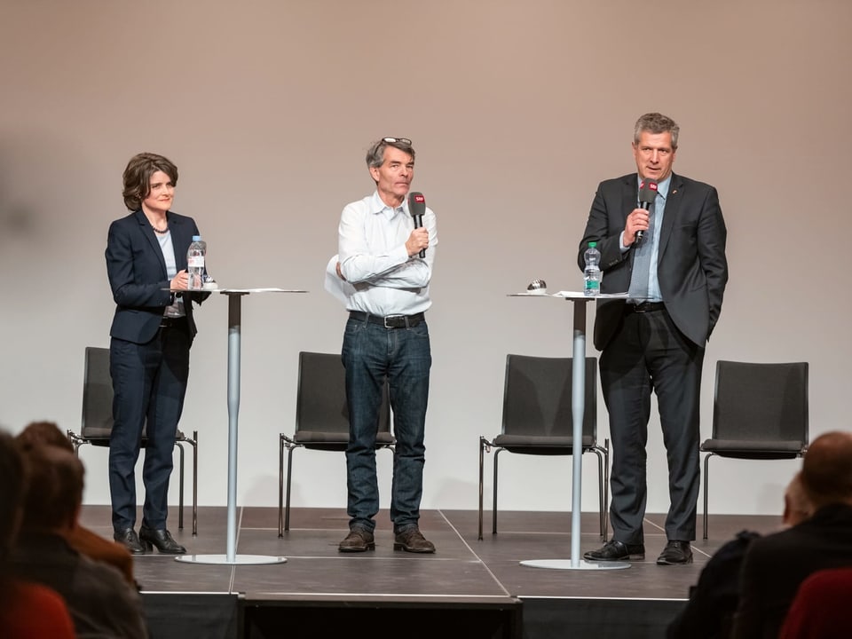 Katrhrin Schweizer, Moderator Dieter Kohler und Thomas de Courten diskutieren stehend.