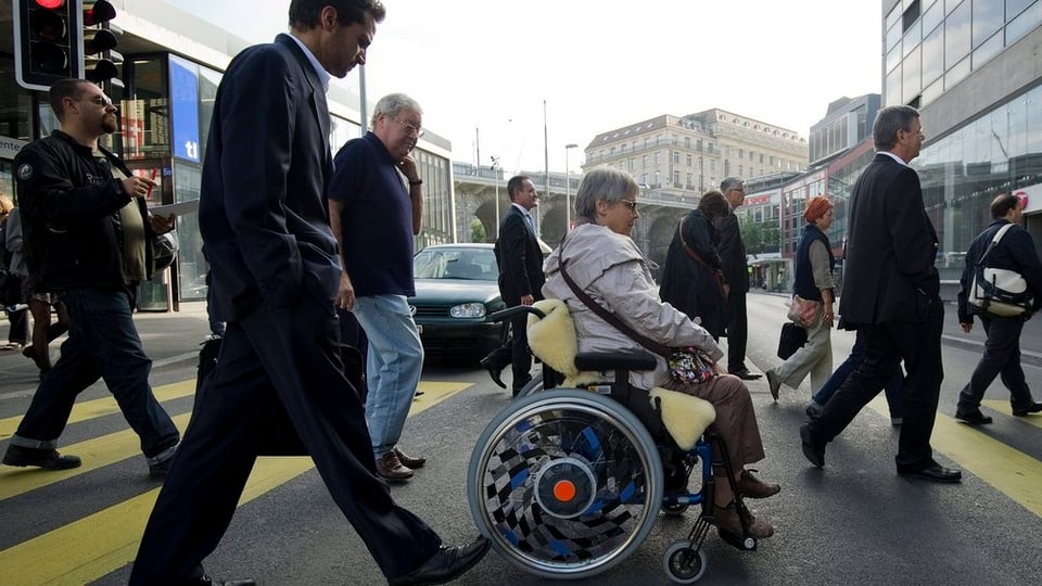 Eine Frau im Rollstuhl überquert die Strasse