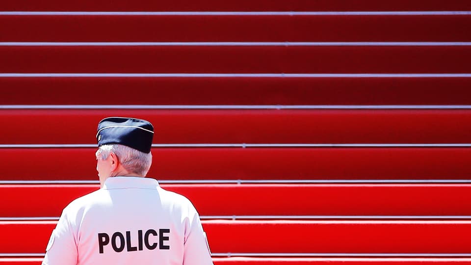 Polizist steht vor Treppe mit rotem Teppich.
