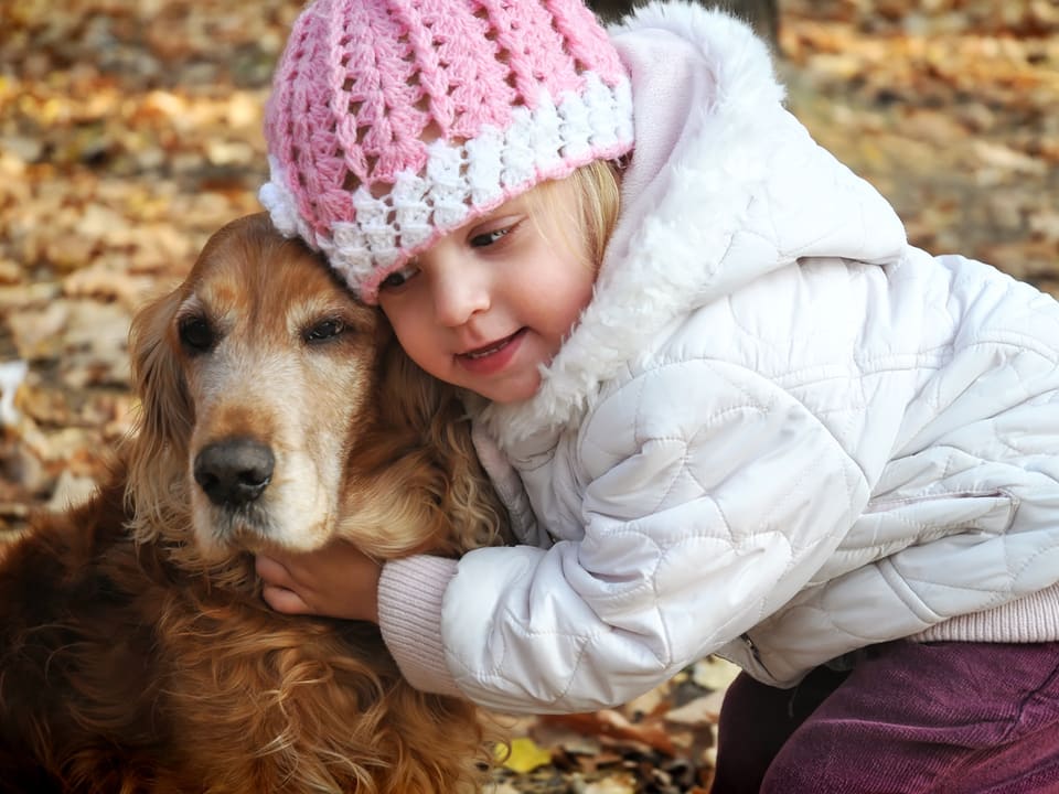 Kleines Mädchen umarmt Hund.