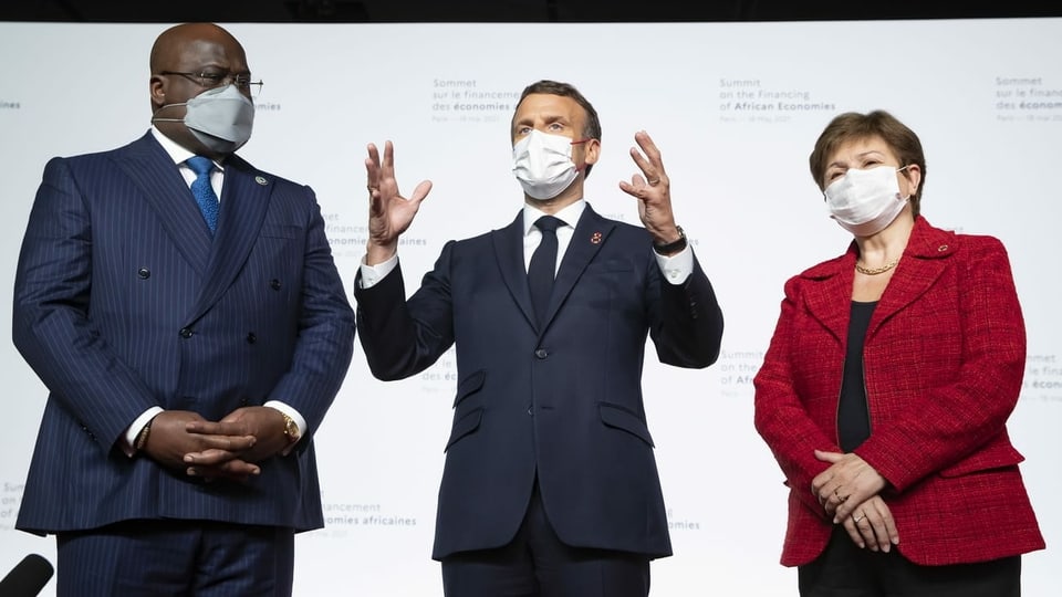 Die drei Personen stehen nebeneinander, Macron in der Mitte gestikuliert.