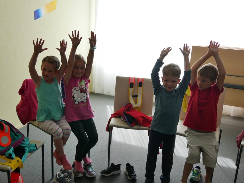 Vier Kinder halten die Hände hoch beim Besuch im Seniorenheim