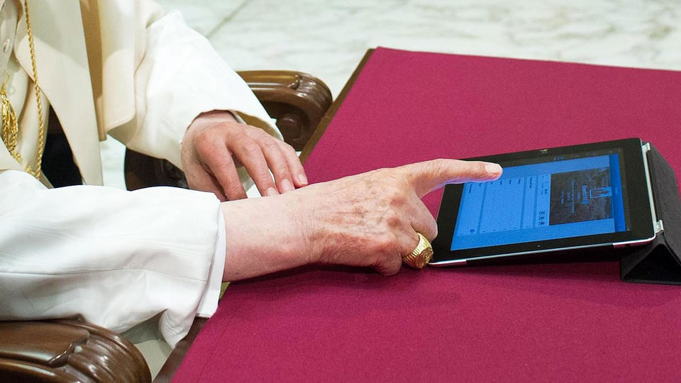 Foto der Hände des Papstes Benedikt, der ein IPad bedient.
