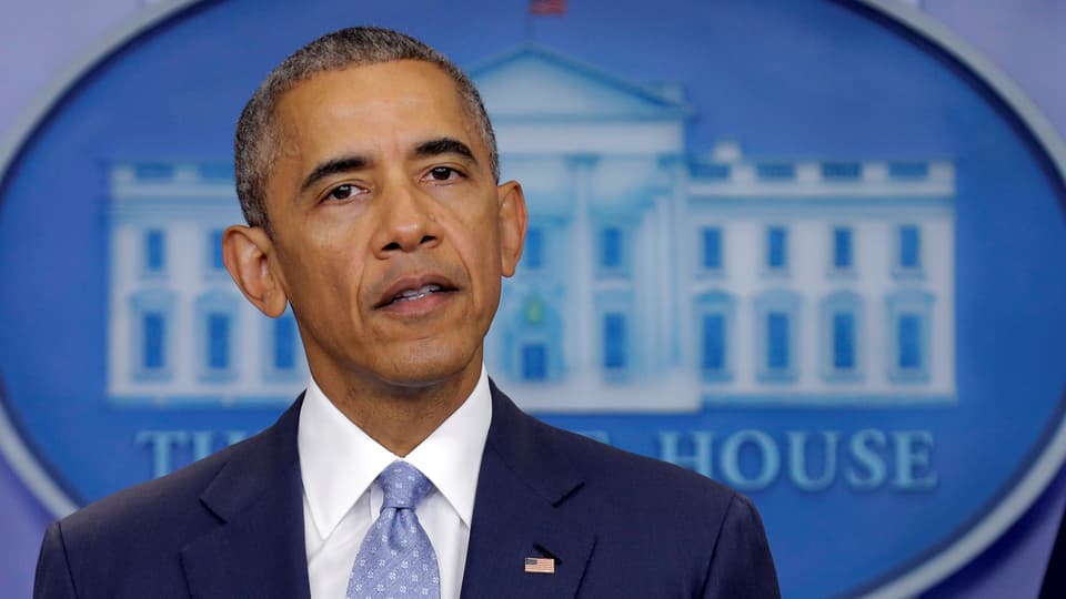 Obama spricht vor dem Emblem des Weissen Hauses.