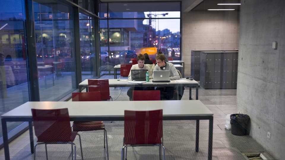 Zwei Studenten arbeiten in einem Arbeitsraum der Universität Freiburg an ihren Laptops.