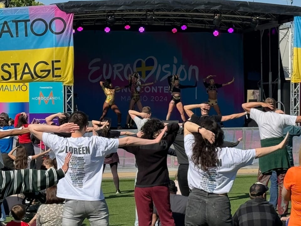 Eurovison-Ereignis in Malmö mit tanzenden Menschen und Bühnenauftritt im Hintergrund.