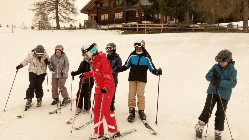 Kinder und ein Skilehrer im Schnee.