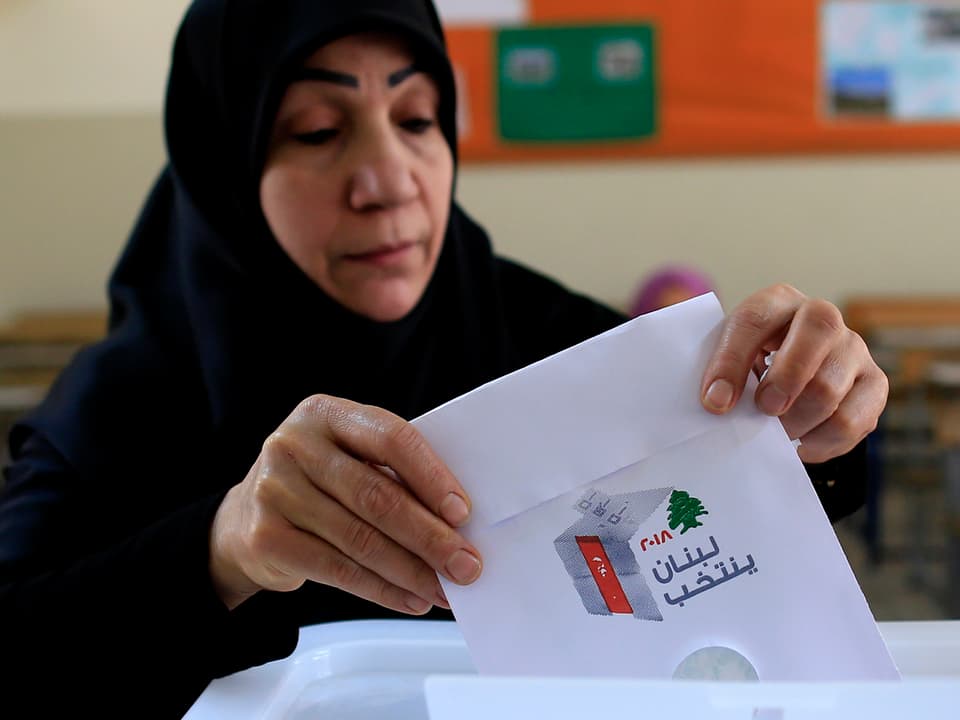 Eine Frau mit Schleier wirft ihren Wahlzettel in die Urne.
