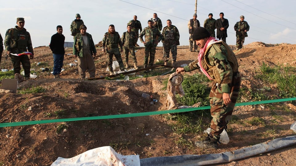 Kurdische Kämpfer an einer Stelle, wo Jesiden exekutiert worden sein sollen.